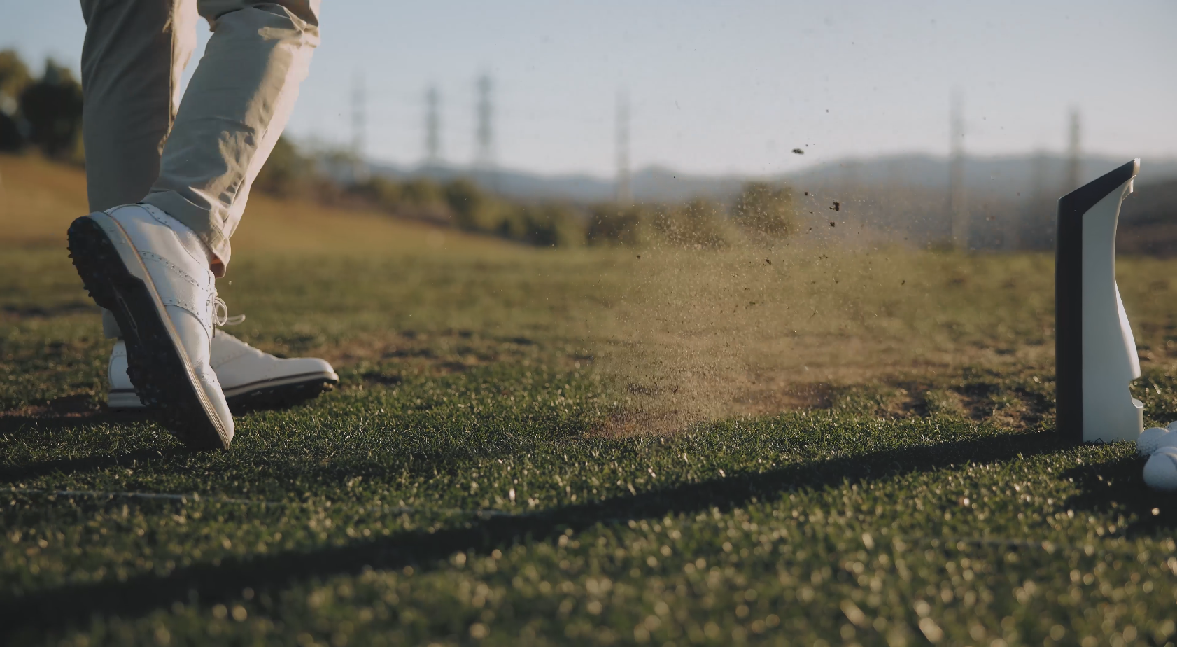 Person playing golf on a grassy field with GOLFJOY Spica 3 launch monitor that providing real-time swing data for outdoor golf practice